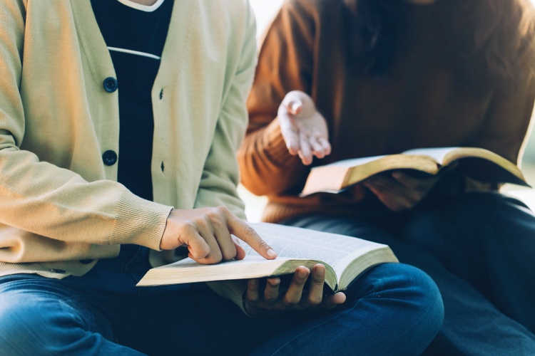 two people sit together discussing a religious text