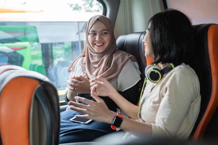 two women chat happily on a charter bus