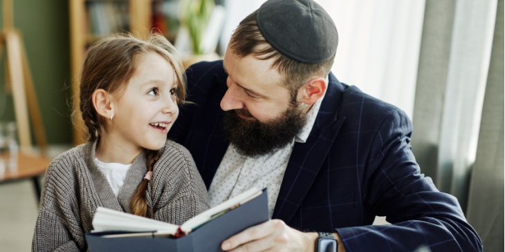 a young girl reads a book with her father