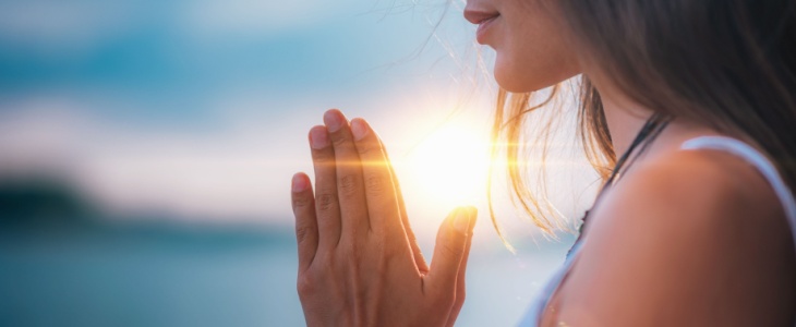 a woman standing with her hands near her heart during a yoga session