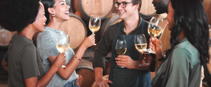 a group of friends enjoy a tasting in the cellar as part of their winery tour