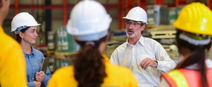 a construction manager has a meeting with four workers, all wearing hard hats